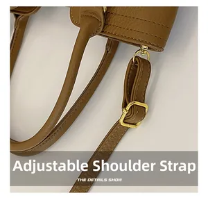 Detail of brown pebbled leather bag featuring stitching and golden adjustable strap buckle