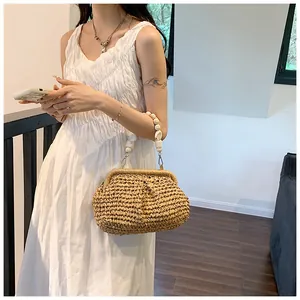 Detail of hand-woven straw bag with shell-bead handle on white dress background