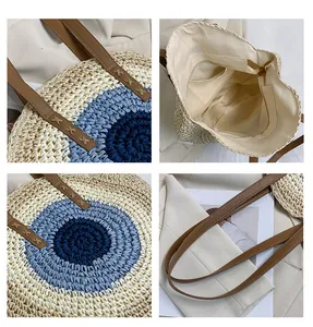 Detail view of round straw beach bag showing blue pattern, inner lining, and brown straps