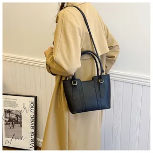 Detail view of black lychee grain leather tote bag with gold hardware and shoulder strap