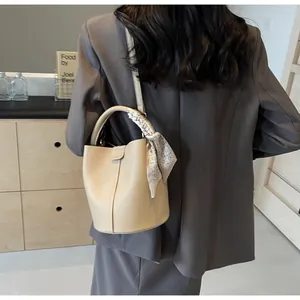 Chic beige bucket bag with textured leather and patterned silk scarf handle detail
