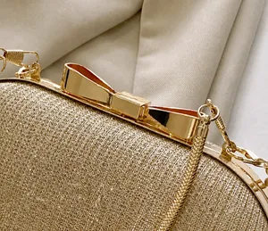 Detail view of the golden glitter fabric and metallic bow-shaped clasp on the clutch