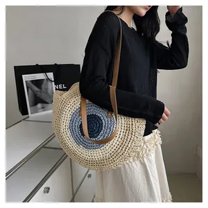 Close-up of beige woven straw tote bag with blue circular patterns and brown shoulder straps