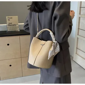 Detail of beige bucket bag with lychee texture leather and decorative silk scarf