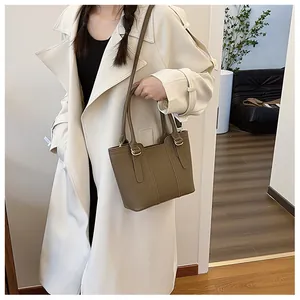 Close-up of a brown leather bucket bag shown on model with tan trench coat for work