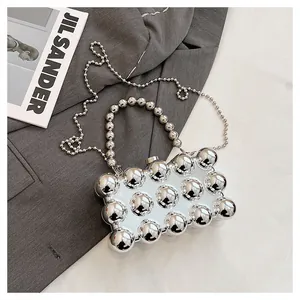 Detail of silver mirror evening bag with large metallic studs and beaded chain strap