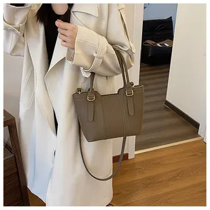 Brown pebbled leather bucket bag styled as a crossbody on a model in a modern room