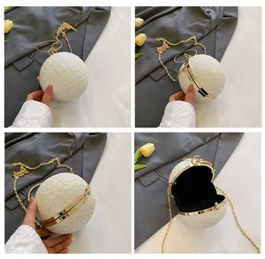 Detail of white spherical evening clutch with gold metal handle and glitter texture finish