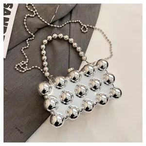 Close-up of a silver spherical acrylic evening bag with mirror finish and bead chain