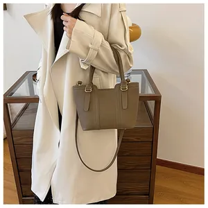Model wearing dark khaki pebbled leather bucket bag with trench coat for commute style