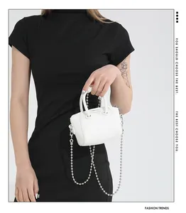 Detail of white lychee pattern mini bag with golden ball chain strap on black dress