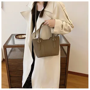 Close-up of khaki pebbled leather bucket bag with top handles and gold hardware details