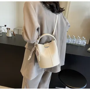 Detail showing cream bucket bag in lychee leather with silk scarf on the handle