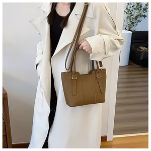 Brown lychee leather handbag with gold metal hardware and adjustable shoulder strap on model