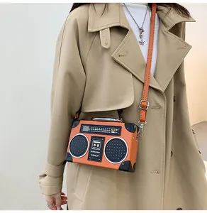 Dettaglio della borsa a tracolla creativa a forma di radio arancione con cappotto beige