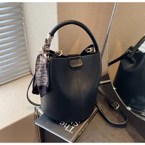Detailed view of black lychee grain bucket bag with silk scarf on the round handle