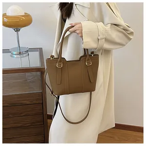 Detailed close-up of brown litchi pattern leather tote with golden metal hardware accents