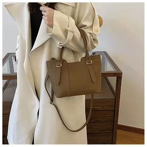Brown lychee grain leather bucket bag shown on a model wearing a beige trench coat