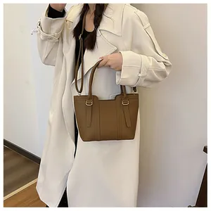 Brown litchi leather bucket bag shown on a beige trench coat for a stylish daily commute
