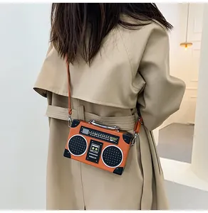 Dettaglio della borsa a tracolla arancione a forma di radio vintage indossata da modella