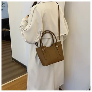 Rear view of model wearing a brown leather bucket bag with a long beige trench coat