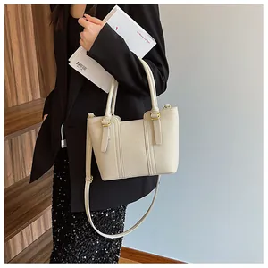 Close-up of beige lychee grain leather bucket bag with gold hardware and shoulder strap