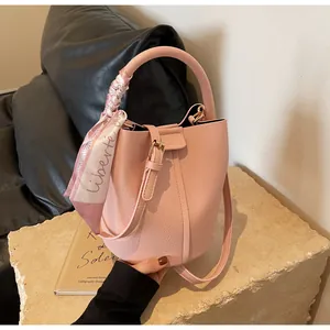 Detail of pink lychee leather bucket bag with decorative silk scarf on the stone pedestal