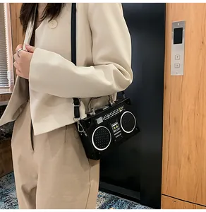 Donna indossa borsa a tracolla vintage a forma di radio con scritta BOOM in ascensore
