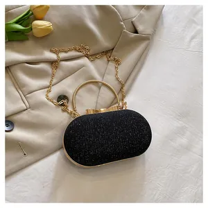Close-up of glittery black evening bag with gold bow clasp on beige blazer