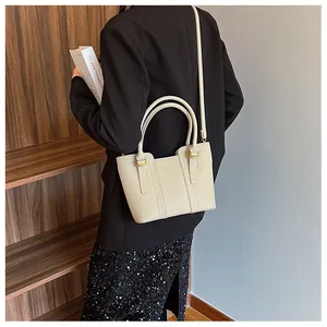 Detail view of cream lychee texture leather handbag with gold hardware and top handles