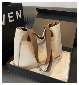 Detail of canvas tote bag with brown straps and side pocket in premium gift packaging