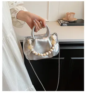 Détail du sac à main argenté avec perles décoratives marbrées et fine bandoulière