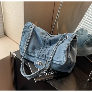 Vue détaillée du sac cabas en denim bleu avec surpiqûres et fermoir rotatif argenté