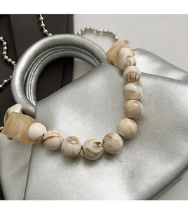 Détail d'une lanière de perles marbrées avec des perles en résine jaune sur sac argenté