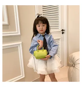 Girl wearing lime green mini Boston bag with silver chain and lychee texture