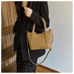 Detail view of brown textured leather bucket bag with gold hardware worn by a model