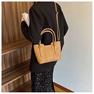 Detailed back view of a camel litchi grain leather bucket bag worn by a model