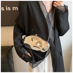 Close-up of a silver liquid metal clutch bag with metallic chain on a model in a black suit