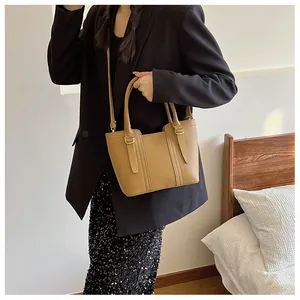 Detail of camel leather bucket bag showing dual handles and crossbody strap texture