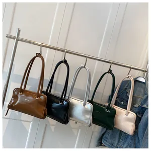 Row of minimalist glossy leather shoulder bags in brown, black, silver, green, and beige