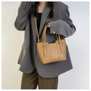 Detail of brown litchi grain leather bucket bag with top handles and adjustable strap