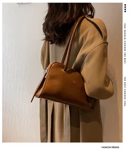 Close-up of caramel glossy leather underarm bag with zipper detail and dual straps