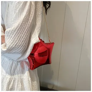 Dettaglio di una borsa a tracolla rossa a forma di stella con sottile catena metallica