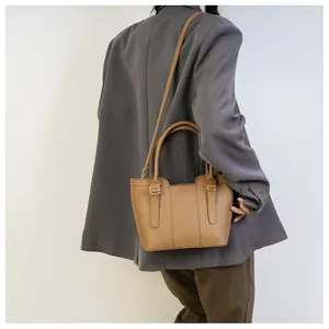 Detailed view of camel leather bucket bag showing lychee grain texture and metal buckles