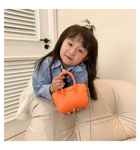 Detailed view of an orange mini child handbag with lychee texture and ring handle