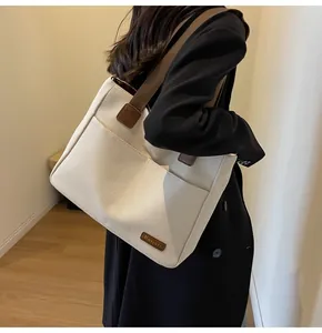 Detail of canvas tote bag showing side view with brown strap and front pocket detail