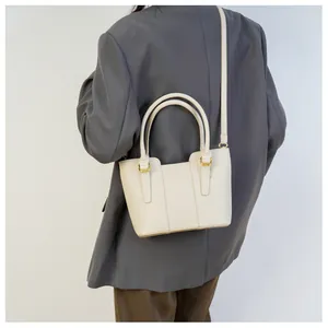 Detail of beige lychee leather bucket bag with top handles and golden hardware