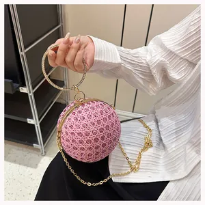 Close-up of pink rhinestone evening bag with gold circular handle and metal frame