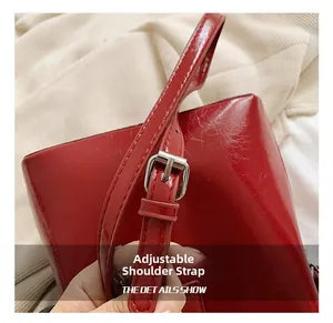 Détail d'un sac seau rouge brillant avec bandoulière réglable et boucle en métal argent