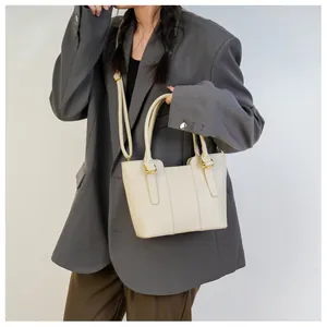 Detail of cream-colored bucket bag showing lychee grain texture and gold hardware